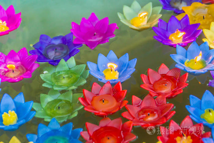 照片 五颜六色的莲花与燃烧的蜡烛漂浮在水面上,以祈祷祝福的方式崇拜