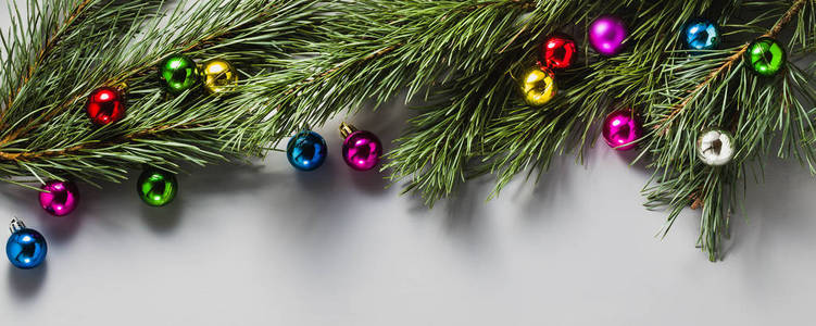 来自圣诞树树枝和圣诞玩具的灰色圣诞背景横幅。复制空间