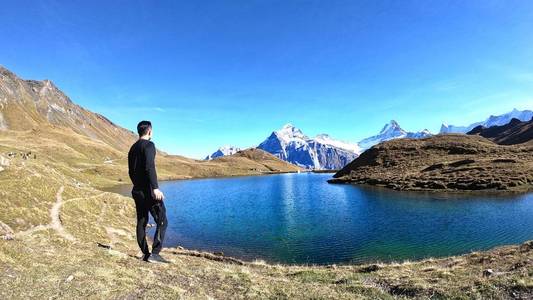 一个男人旅行者放松和寻找高峰山与蓝天和云背景在grindelwaldswiss。愉快的假期在美丽的户外场景景观。旅行自由的概念。