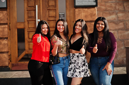 来自厄瓜多尔的四个快乐漂亮的拉丁女孩在街上摆姿势，并一起展示拇指。