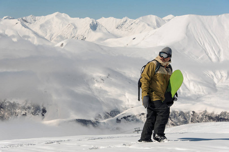 一个人站在山上的滑雪板上，看着流行的旅游胜地的照相机
