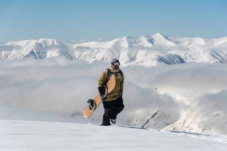 在乔治亚州著名的旅游胜地，一个男子滑雪板手拿着滑雪板在山上行走