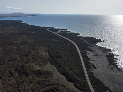 西班牙拉扎罗特岛加那利群岛浮雕火山和熔岩场的鸟瞰图。 崎岖的海岸线和沿着大海行驶的道路