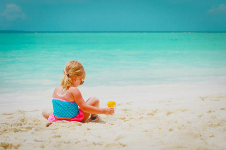 防晒在海滩小女孩与防晒霜奶油在肩膀