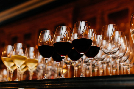 桌子上有许多装满白葡萄酒和红酒的玻璃杯。 深色。 收集葡萄酒。 水平射击。 酒杯中的饮料