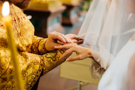 在基督教会举行婚礼时，牧师戴上戒指，在新娘手上摆姿势，在前台点燃蜡烛