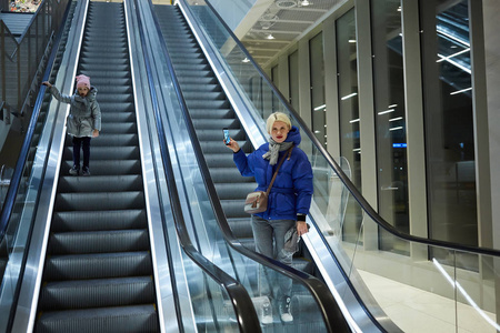 母亲和孩子一起在自动扶梯背景上。航站楼, 机场旅游, 关爱