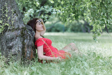 美丽年轻的白种人女孩在外面的树下放松