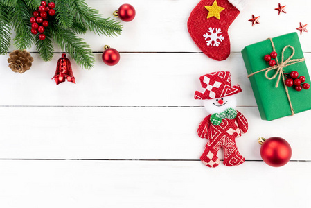圣诞节背景概念。 顶部的圣诞绿色礼品盒与雪人装饰云杉枝，松果，红色浆果和铃铛白色木制背景。