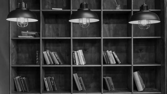 黑白照片。 图书馆。 书架上有书和三盏燃烧的灯。 几本书。 概念图书馆教育阅读