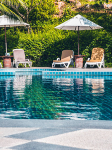 酒店和度假胜地豪华室外游泳池周围的雨伞和椅子，供度假和旅行使用