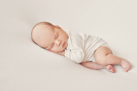可爱的新生婴儿躺在白色的毯子里。 婴儿用品包装模板。 新生儿特写肖像，脸上带微笑。 健康和医学概念。