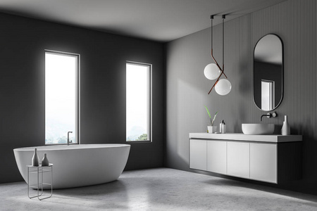 现代浴室的角落，灰色的墙壁，混凝土地板，白色浴缸站在阁楼窗口和白色水槽在灰色的台面上。3D渲染