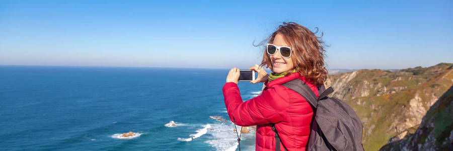 一位身穿罗卡角夹克的漂亮年轻女子在一次移动电话冬季葡萄牙之旅中拍摄风景