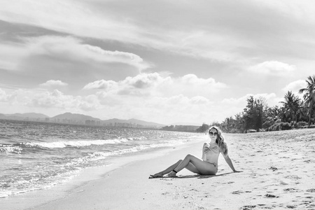 穿着比基尼的漂亮女孩在一个荒芜的海滩上摆姿势。白沙, 绿松石海和一个年轻的女孩
