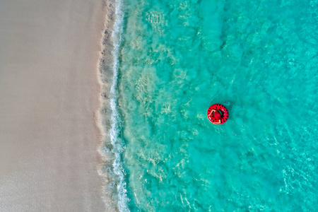 鸟瞰苗条的女人在塞舌尔透明的绿松石海中游泳圈甜甜圈。 夏天海景与女孩美丽的波浪，五颜六色的水。 无人驾驶飞机的俯视图