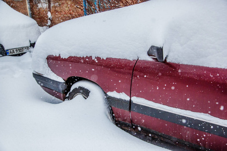 在停车场的冬季暴风雪中，车辆被雪覆盖。白雪覆盖的道路和城市的街道。
