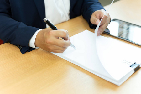商人用钢笔在办公桌上签合同