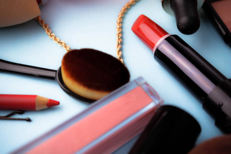 一套女性化妆品从口红, 荧光笔, 唇衬, 刷子, 刷子, 香水, 粉末, 首饰在蓝色背景。美容盒平躺。顶视图