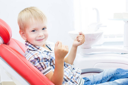 牙科诊所。 病人的接待检查。 牙齿护理。 一个带牙线的小男孩坐在牙科椅上。 口腔卫生概念。
