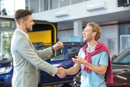 推销员与顾客握手，同时给汽车经销商钥匙