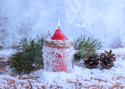 白雪覆盖的木制背景上的红烛枝和锥
