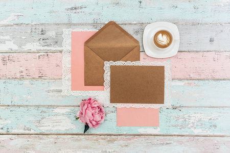 平躺着贺卡模型和信封与粉红色牡丹花和一杯咖啡在老式背景。