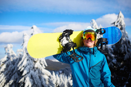 微笑着的滑雪者在森林附近的滑雪胜地肩上摆起肩上的滑雪板, 然后在回乡自由人面前, 穿着反光护目镜, 五颜六色的时尚服装。现代化的