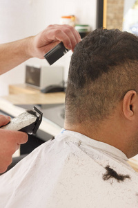男子在理发店用剪头机剪短头发
