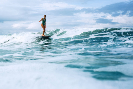 美丽的冲浪女孩骑在巴厘岛海洋的木板上