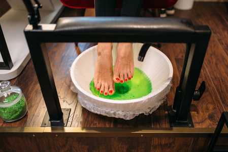 女性客户的脚在足疗浴，顶部视图，美容程序在美甲沙龙。专业指甲及足部皮肤护理