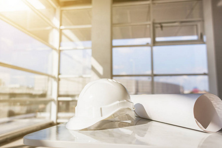 白色头盔, 在一个建筑工地上的建筑的蓝图在窗口背景