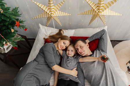在一个晴朗的圣诞节早晨, 幸福的家庭躺在床上。2019年新年
