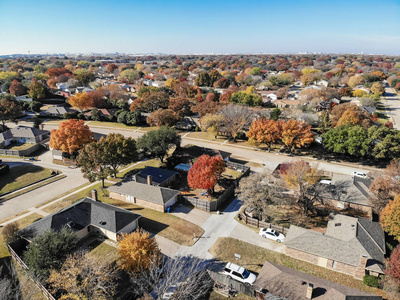 俯视美丽的社区在科佩尔德克萨斯美国秋季季节。 一排独栋的家庭住宅，附属的车库花园，环绕着蓝天下五颜六色的落叶