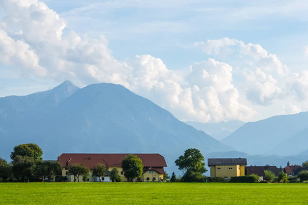 奥地利阿尔卑斯山阳光明媚的一天。背景是山和云的绿色草地。