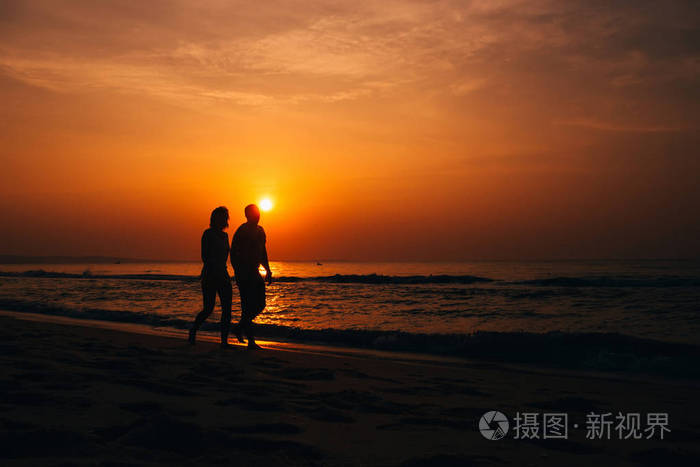 一对恋爱中的情侣在海边海滩上的剪影