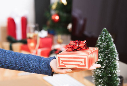 女商人手拿礼品盒在圣诞假期在办公室与圣诞节装饰在桌子上。