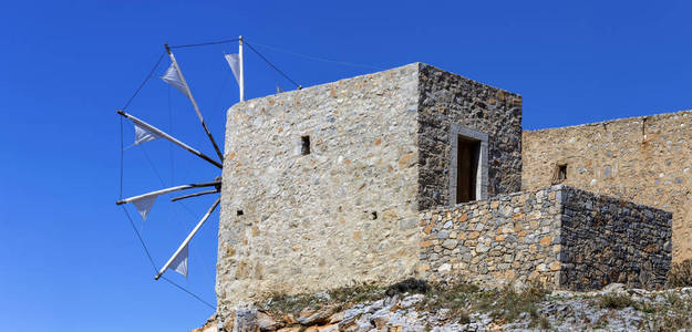 在阳光明媚的日子里，古老的历史上著名的破旧的石制风车拉西提岛希腊克里特岛
