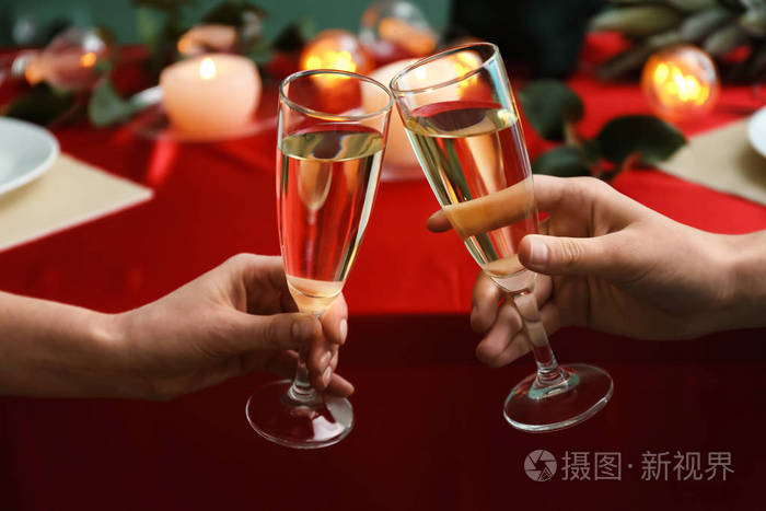 在节日的餐桌上,年轻的人们正拿着香槟碰杯