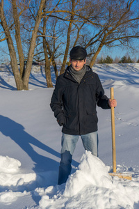 英俊的中年白种人清理家庭地块上的雪