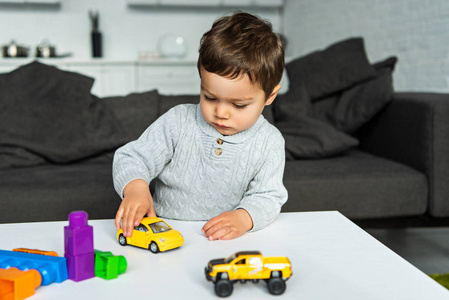 小孩在家里客厅的桌子上玩玩具车的选择性注意力