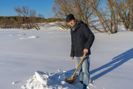 英俊的中年白种人清理家庭地块上的雪