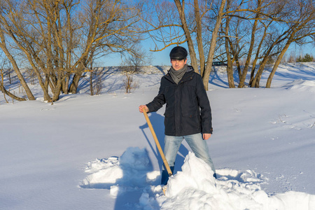 英俊的中年白种人清理家庭地块上的雪