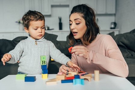 可爱的小男孩和他的母亲在家玩积木木塔游戏