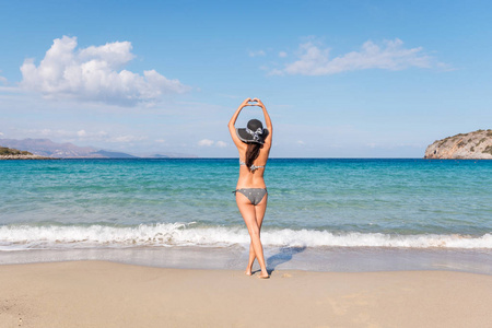 阳光明媚的一天，年轻的女人穿着泳衣在海滩上。