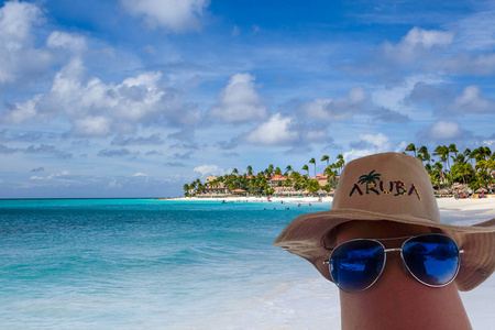 太阳镜和 aruba 帽子在腿上。背景中的鹰海滩