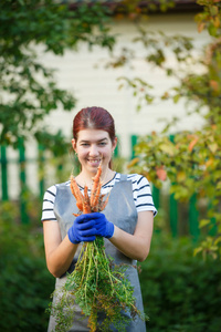 微笑的妇女的相片与胡萝卜在手在庭院