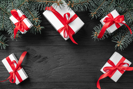 圣诞贺卡与白色的礼物和冷杉树枝在一个黑暗的木质质朴的背景, 文本的地方。圣诞节和快乐的新年贺卡。顶视图, 平面布局