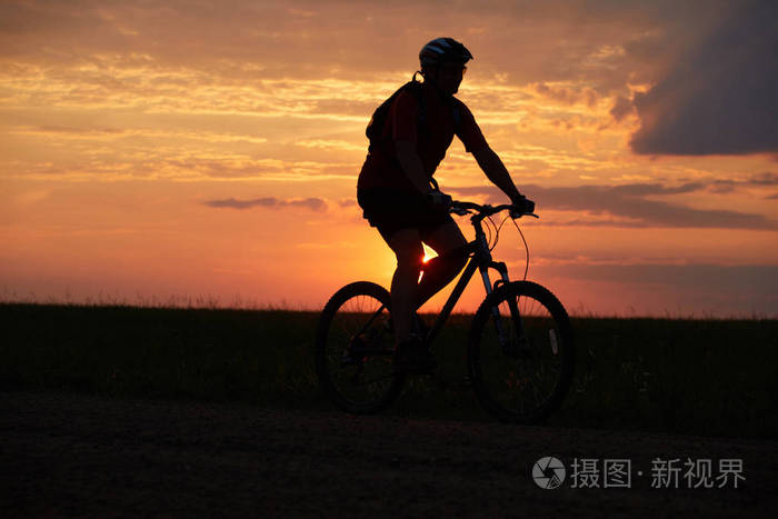 日落背景下骑自行车的剪影.比克尔晚上骑在路上.室外红黄色背景