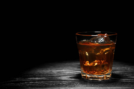 黑底木桌上加冰的威士忌